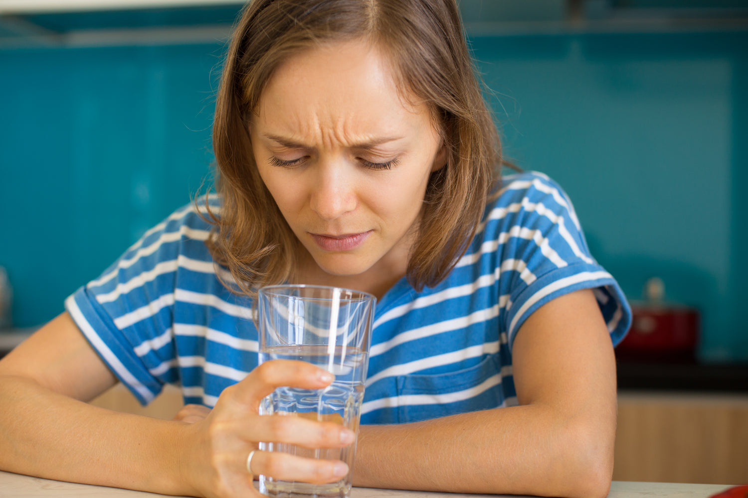 Woman looking at a glass of water with concern.